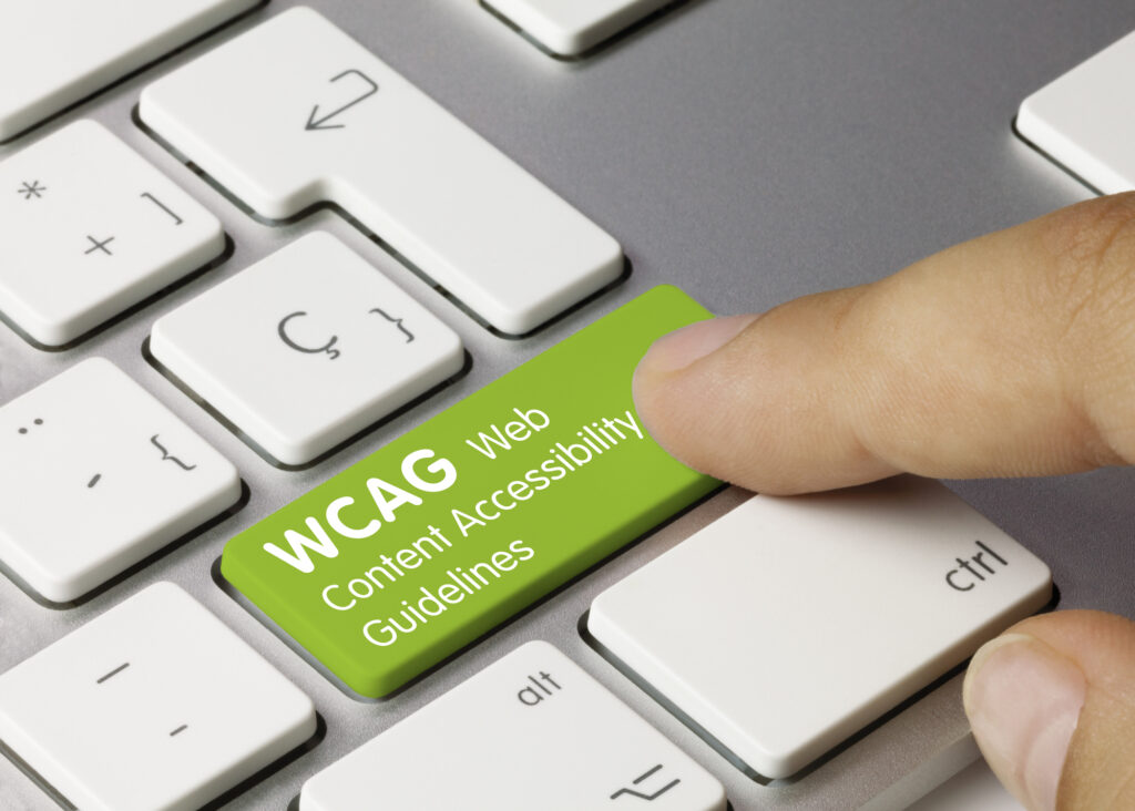 WCAG Web Content Accessibility Guidelines skrevet på en grønn knapp på et PC-tastatur med en finger som trykker på den