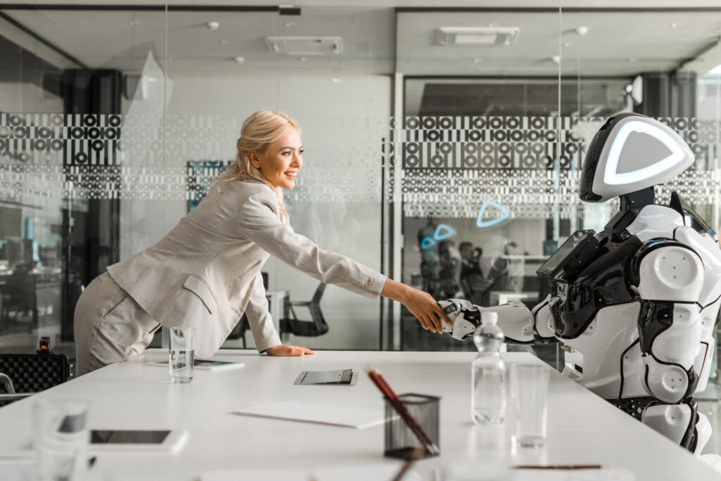 Kvinne håndhilser på en robot på en moderne arbeidsplass
